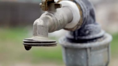 Doğanın arka planında su musluğu var. Su tasarrufu için musluğu açmak ya da kapatmak su sıkıntısı olduğunu gösterir. Gün ışığıyla taşra çeşmesi. Bulanık arkaplan ile seçmeli odak