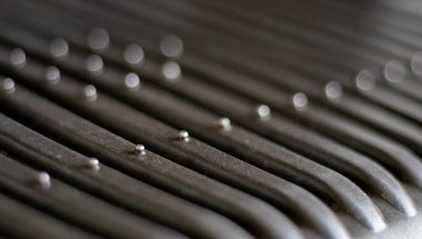 Black electric grill grate, textured background. The surface of the electric grill. Pollution of the surface of the electric stove. Close-up of a home electric grill, in the kitchen. BBQ