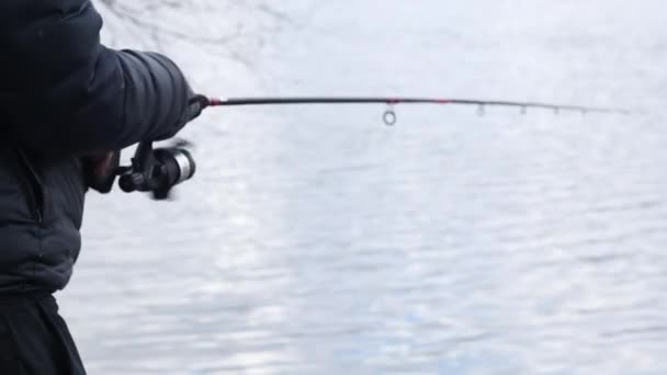 漁をしながらリールを回転させる男の手で釣竿のクローズアップ 川や湖の近くに釣竿を持つ認識できない漁師 ウクライナ キエフ 2023年3月5日 — ストック動画