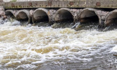 Borulardan nehire pis kokulu, kirli atık su taşıyan beton bir boru. Çevre ve su kaynaklarının kirliliği. Ekolojik felaket. Tehlikeli atık su
