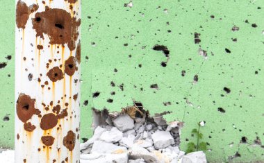 Cephedeki duvarda kurşun delikleri ve şarapnel parçaları var. Savaş yaraları. Çukur ve kurşun delikleriyle dolu bir binanın beton duvarı. Ukrayna 'daki savaşın sonuçları