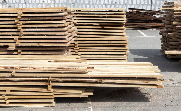 Pile of stacked wooden planks at a construction site. Wooden boards, lumber. Industrial edged timber. Wooden rafters for the repair or construction of a private house. Roofing and joinery lumber