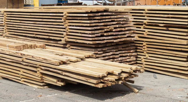 Pile of stacked wooden planks at a construction site. Wooden boards, lumber. Industrial edged timber. Wooden rafters for the repair or construction of a private house. Roofing and joinery lumber