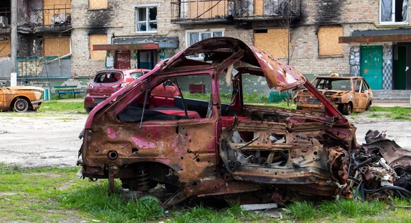stock image The car that burned down after the bombing of the city stands in the courtyard of a destroyed house. War between Russia and Ukraine. Fragments of a car after artillery shelling