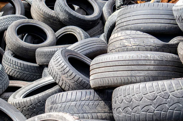 stock image Garbage from a pile of black old car tires. Environmental pollution. Ecological problems. Old car tires thrown into an industrial landfill for recycling. Reuse of worn rubber tires