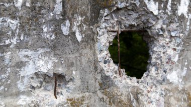 Kırık bir beton duvarın ya da çitin fotoğrafı. Üzerinde delik olan garip bir duvar. Bozuk çatlak ve kırık beton duvar