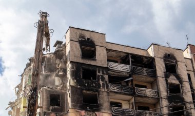 Konut binasının yıkımında hidrolik ezicili bir kazıcı. Şehir yenilenmesi. Parçalara ayırmak, çok katlı bir binayı yeniden inşa etmek için yıkmak. Enkaz temizleniyor.