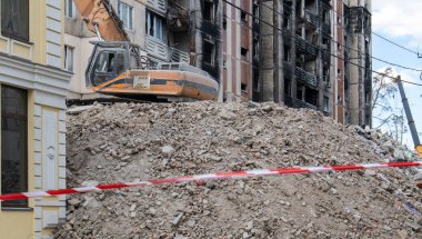Çok katlı apartmanların yıkımı üzerine inşaat çalışması. Kırmızı ve beyaz uyarı bandından yapılmış. Konut binasının yıkımında hidrolik parçalayıcı ile kazıcı