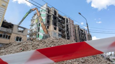 Yüksek katlı bir binanın yıkılması. Bir yerleşim yerinin çökmesi. Yüksek katlı apartmanların yıkımı üzerine inşaat çalışması. Kırmızı ve beyaz uyarı bandından yapılmış bir çit