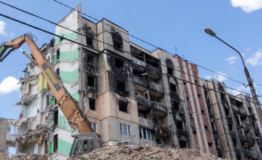 Yüksek katlı bir binanın yıkılması. Bir yerleşim yerinin çökmesi. Çok katlı apartmanların yıkımı üzerine inşaat çalışması. Hidrolik ezicili kazıcı