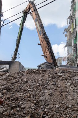 Binanın eski sökülme sürecinin yıkılması süreci. Kazı makinesi evi dağıtıyor. Harap olmuş konutların yıkılması. İnşaat kazıcısı tadilat için bir evi yıkıyor
