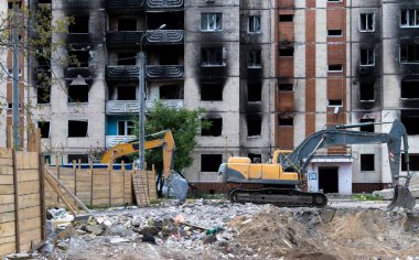 Şiddetli bir yangından sonra terk edilmiş çok katlı bir binanın ön cephesi. Hidrolik ezicisi olan bir inşaat kazıcısı tamir için bir evi yıkıyor. Bir yerleşim yerinin çökmesi.