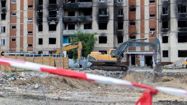 Çok katlı apartmanların yıkımı üzerine inşaat çalışması. Kırmızı ve beyaz uyarı bandından yapılmış. Harap olmuş konutların yıkılması. Büyük bir yangından sonra konut binası. Şehir yenilenmesi