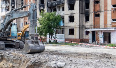 Çok katlı apartmanların yıkımı üzerine inşaat çalışması. Kırmızı ve beyaz uyarı bandından yapılmış. Harap olmuş konutların yıkılması. Büyük bir yangından sonra konut binası. Şehir yenilenmesi