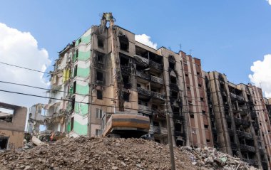 Konut binasının yıkımında hidrolik ezicili bir kazıcı. Şehir yenilenmesi. Parçalara ayırmak, çok katlı bir binayı yeniden inşa etmek için yıkmak. Enkaz temizleniyor.