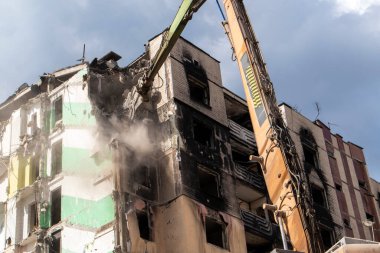 Yüksek katlı bir binanın yıkılması. Bir yerleşim yerinin çökmesi. Çok katlı apartmanların yıkımı üzerine inşaat çalışması. Hidrolik ezicili kazıcı