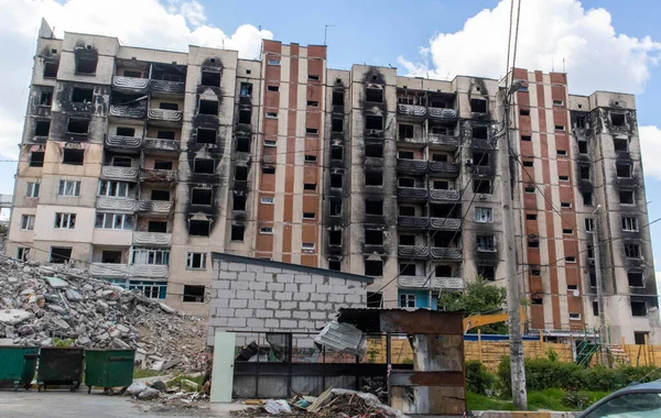 stock image Facade of a residential abandoned multi-storey building after a strong fire. A construction excavator with a hydraulic crusher demolishes a house for repairs. The collapse of a residential building