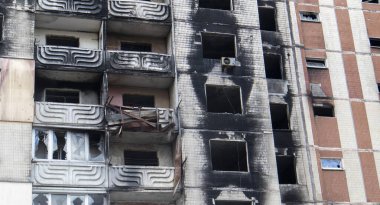 The destruction of a multi-storey building after being hit by an artillery shell. A burned-out high-rise building in a war zone. War in residential areas, broken windows and burnt apartments