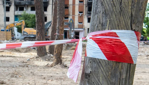 Demolition of a high-rise building. The collapse of a residential building. Construction work on the demolition of high-rise apartments. Fence made of red and white warning tape
