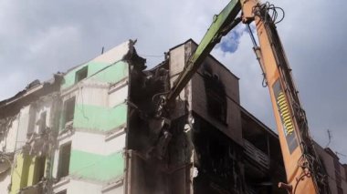 Yüksek katlı bir binanın yıkılması. Bir yerleşim yerinin çökmesi. Çok katlı apartmanların yıkımı üzerine inşaat çalışması. Hidrolik ezicili kazıcı