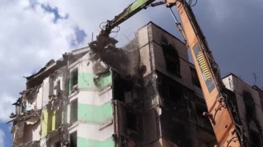 Konut binasının yıkımında hidrolik ezicili bir kazıcı. Şehir yenilenmesi. Parçalara ayırmak, çok katlı bir binayı yeniden inşa etmek için yıkmak. Enkaz temizleniyor.