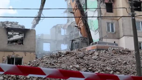 多階建てのアパートの解体に関する建設作業 赤および白い警告テープから成っている塀 家の取り壊しで油圧粉砕機が付いている掘削機 ウクライナ イルピン 2023年5月12日 — ストック動画