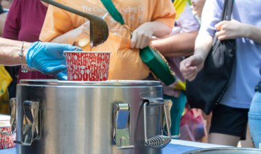Makarnalı domates çorbası bir Polonya yemeğidir. Zupa pomidorowa. Rendelenmiş domateslerden yapılan sıcak çorba. İnsanlar ve turistler sokak yemekleri festivalinde yürüyor, yiyor ve yemek alıyorlar. Ukrayna, Kyiv - 17 Ağustos 2023