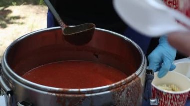 Makarnalı domates çorbası bir Polonya yemeğidir. Zupa pomidorowa. Rendelenmiş domateslerden yapılan sıcak çorba. İnsanlar ve turistler sokak yemekleri festivalinde yürüyor, yiyor ve yemek alıyorlar. Ukrayna, Kyiv - 17 Ağustos 2023