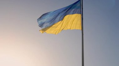Ukrayna bayrağı. Gökyüzünde dalgalanan büyük bir Ukrayna bayrağının yavaş hareketi. Ukrayna 'nın mavi ve sarı ulusal sembolü. Bayrak direğinde büyük bir bayrak