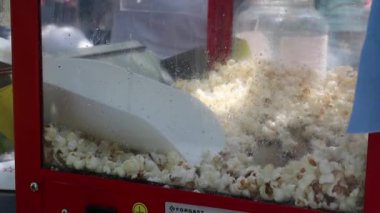 Bilinmeyen eliyle patlamış mısır kaşıklayan klasik bir patlamış mısır makinesi. Konukların eğlenmesi için patlamış mısırlar torbaya doldurulur. Patlamış mısır ve kepçe üreticisi. Ukrayna, Kyiv - 17 Ağustos 2023