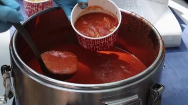 Makarnalı domates çorbası bir Polonya yemeğidir. Zupa pomidorowa. Rendelenmiş domateslerden yapılan sıcak çorba. İnsanlar ve turistler sokak yemekleri festivalinde yürüyor, yiyor ve yemek alıyorlar. Ukrayna, Kyiv - 17 Ağustos 2023