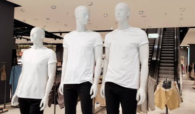 Şehir merkezindeki bir alışveriş merkezinde modern bir moda mağazasının vitrini. Metnin için fotokopi alanı olan beyaz tişörtlü üç manken.