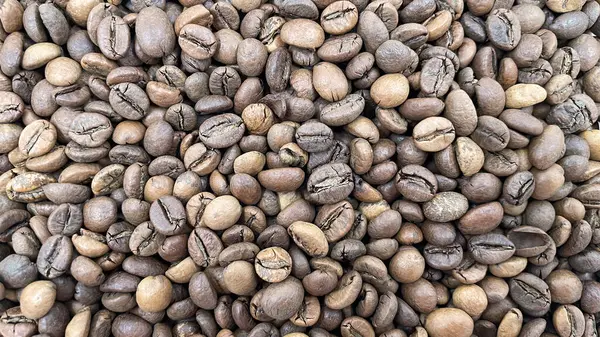 Roasted coffee beans can be used as a background. Top view of aromatic brown coffee beans scattered on the surface. Halves of dark brown coffee beans with a pleasant aroma