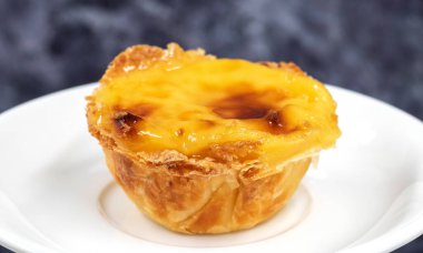 Beyaz tabakta bir Pastel de nata veya Portekiz yumurtalı turtası. Pastel de Belm çıtır börek hamurlu ve kremalı küçük bir turta.