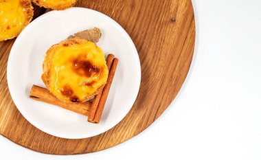 Pastel de nata tartları ya da Portekiz yumurtalı tart ve tarçın çubukları beyaz arka planda izole edilmiş. Pastel de Belem çıtır börek hamurlu ve kremalı küçük bir turta.