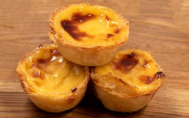 Pastel de nata turtaları ya da kahverengi arka planda Portekiz yumurtalı turtası. Pastel de Belem çıtır börek hamurlu ve kremalı küçük bir turta. Tatlı tatlı
