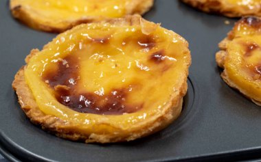 Fırında pişmiş taze Pastel de nata ya da Portekiz yumurtalı tart tatlısı var. Pastel de Belme çıtır börek hamurlu ve kremalı küçük bir turta. Küçük kek.