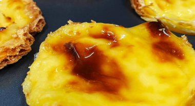 Fırında pişmiş taze Pastel de nata ya da Portekiz yumurtalı tart tatlısı var. Pastel de Belme çıtır börek hamurlu ve kremalı küçük bir turta. Küçük kek.