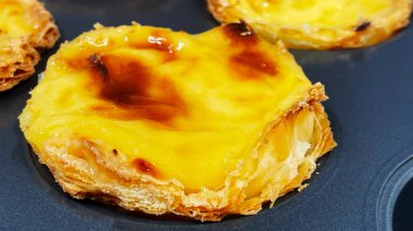 Fırında pişmiş taze Pastel de nata ya da Portekiz yumurtalı tart tatlısı var. Pastel de Belme çıtır börek hamurlu ve kremalı küçük bir turta. Küçük kek.