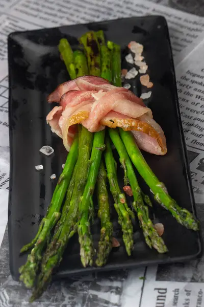 Gazete arka planında kuşkonmaz sarılmış lezzetli pastırma. 