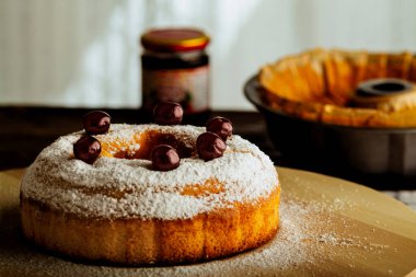 Ev yapımı tatlı pasta, üzerine kiraz serpiştirilmiş şeker tozu. 
