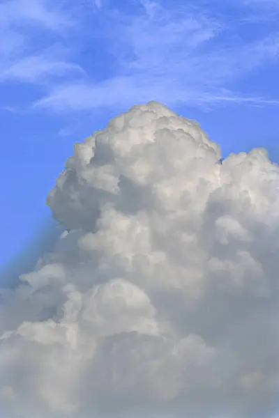 Hareketli mavi gökyüzüne doğru yükselen beyaz bulutların sakin ve huzurlu bir atmosferi resmeden bir fotoğrafı..