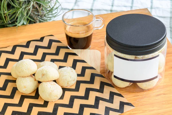 Plastik kutuda kurabiyeler, arka bahçedeki ahşap masada bir fincan sade kahvenin yanında.