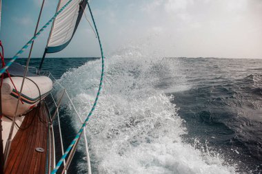 Dalgalar arasında yelkenliyle yelken açmak dalgalı bir denizde, bir sürü sıçrama.