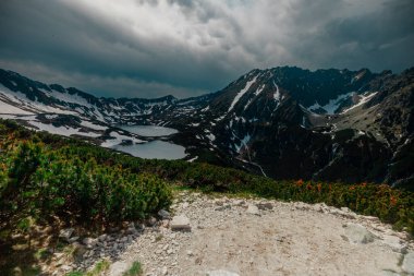 Dağlarda güzel bir gölü olan dramatik gökyüzü ve bulutları olan bir manzara.
