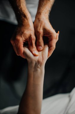 Bir spa terapisti genç bir bayana rahatlatıcı bir el masajı yapar, ona dokunur ve bir güzellik salonunun içinde sıvazlar.