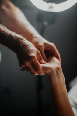 Bir spa terapisti genç bir bayana rahatlatıcı bir el masajı yapar, ona dokunur ve bir güzellik salonunun içinde sıvazlar.