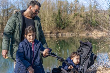 Babamın puset ve iki çocuğuyla baharda Aare nehri boyunca yürüdüğü yakın plan..