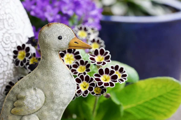 stock image little tin goose standing between spring flowers