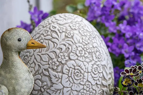 stock image little tin goose with big ornamented egg and lilac spring flowers